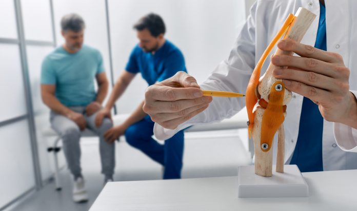 Zwei Fachpersonen beraten Patienten zu Behandlung seiner Knieverletzung