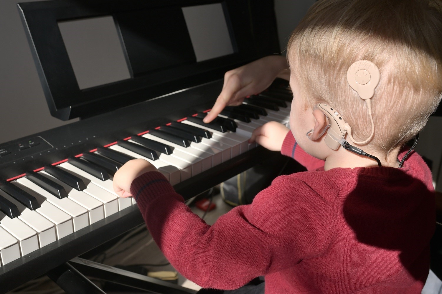 Ein Kind mit Cochlea-Implantat beim Klavier spielen.