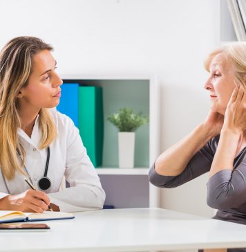 Eine Frau klagt in der Sprechstunde mit ihrer Ärztin über Ohrenschmerzen.