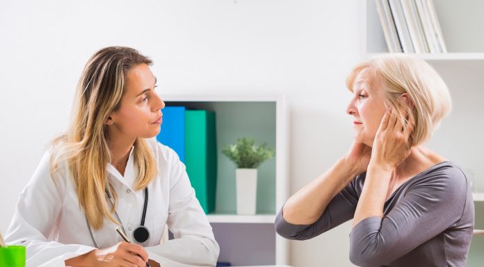 Eine Frau klagt in der Sprechstunde mit ihrer Ärztin über Ohrenschmerzen.